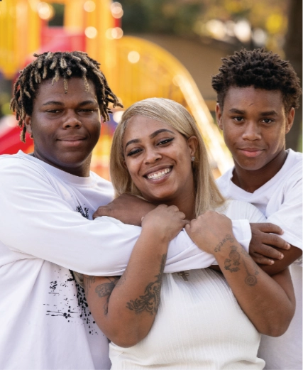 A mother with her two teenage sons outside their home